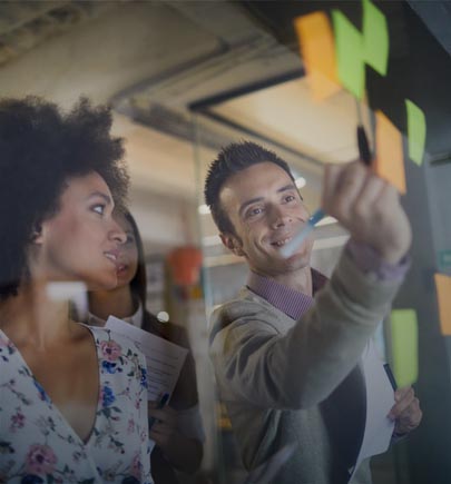 Business man writing on sticky notes on glass wall and a woman watching